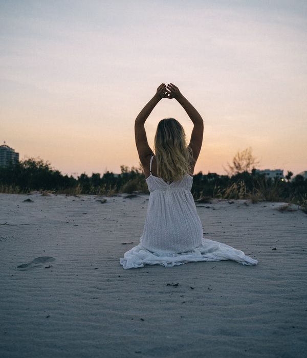 Person meditating peacefully outdoors during sunset.